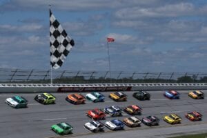 Brad Keselowski, Kyle Busch and Ryan Blaney lead a pack of cars at spring Talladega Cup race, large checkered flag featured, Photo Sean Gardner Getty Images