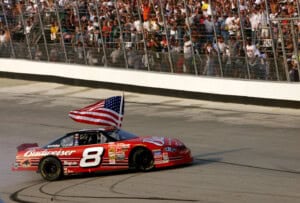 Dale Earnhardt Jr. carries a flag as he burns the tires of his #8 Budweiser Cheverolet Monte Carlo following his win in the MBNA-Cal Ripken Jr. 400 at Dover Downs International Speedway in Dover, Delaware. Digital Image.